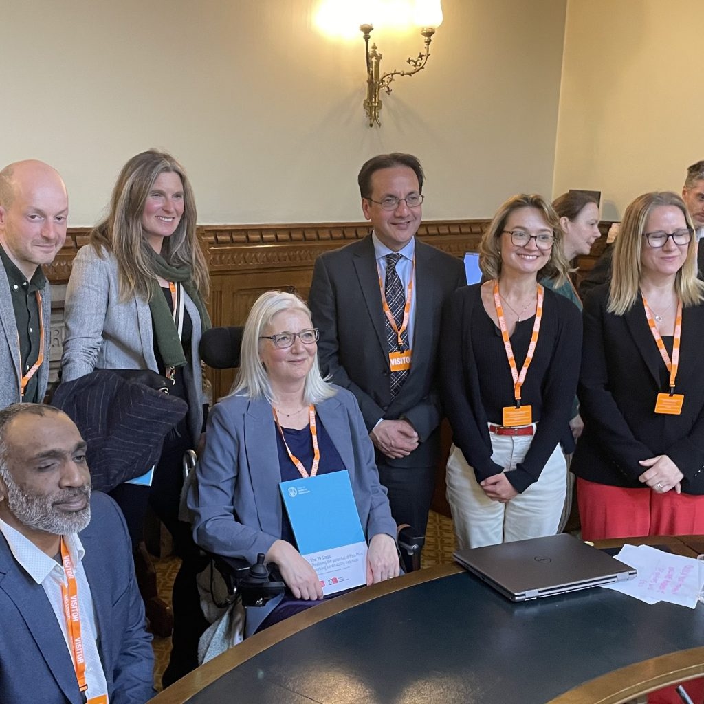 6 colleagues are sat and stood around Catherine Hale while she holds the Flex Plus report.